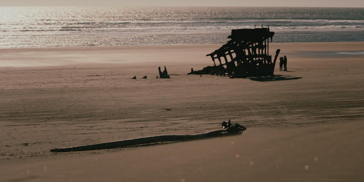 The rusted hull of the Peter Iredale on the beach at dusk.